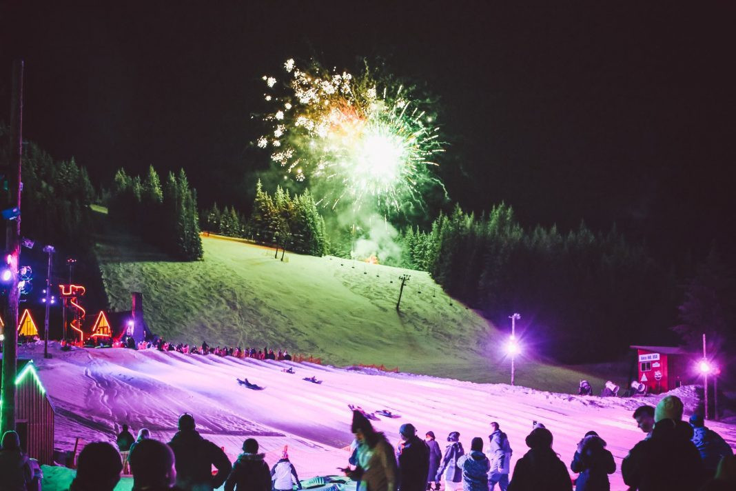 Cosmic Tubing at Mt. Hood Skibowl with colorful lights illuminating snow tubing lanes and fireworks in the night sky