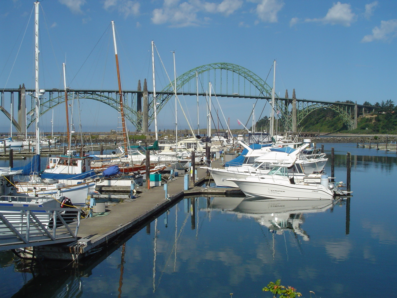 Yaquina Bay marina at Newport, Oregon, with charter boats lined up in front of the iconic green Yaquina Bay Bridge.