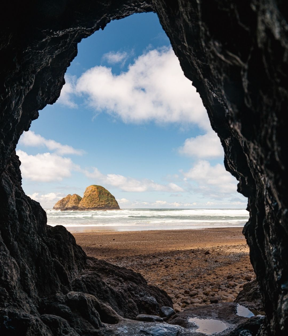 View through the natural arch of Maxwell Point Tunnel looking out at sea stacks and the Pacific Ocean from Tunnel Beach near Oceanside, Oregon