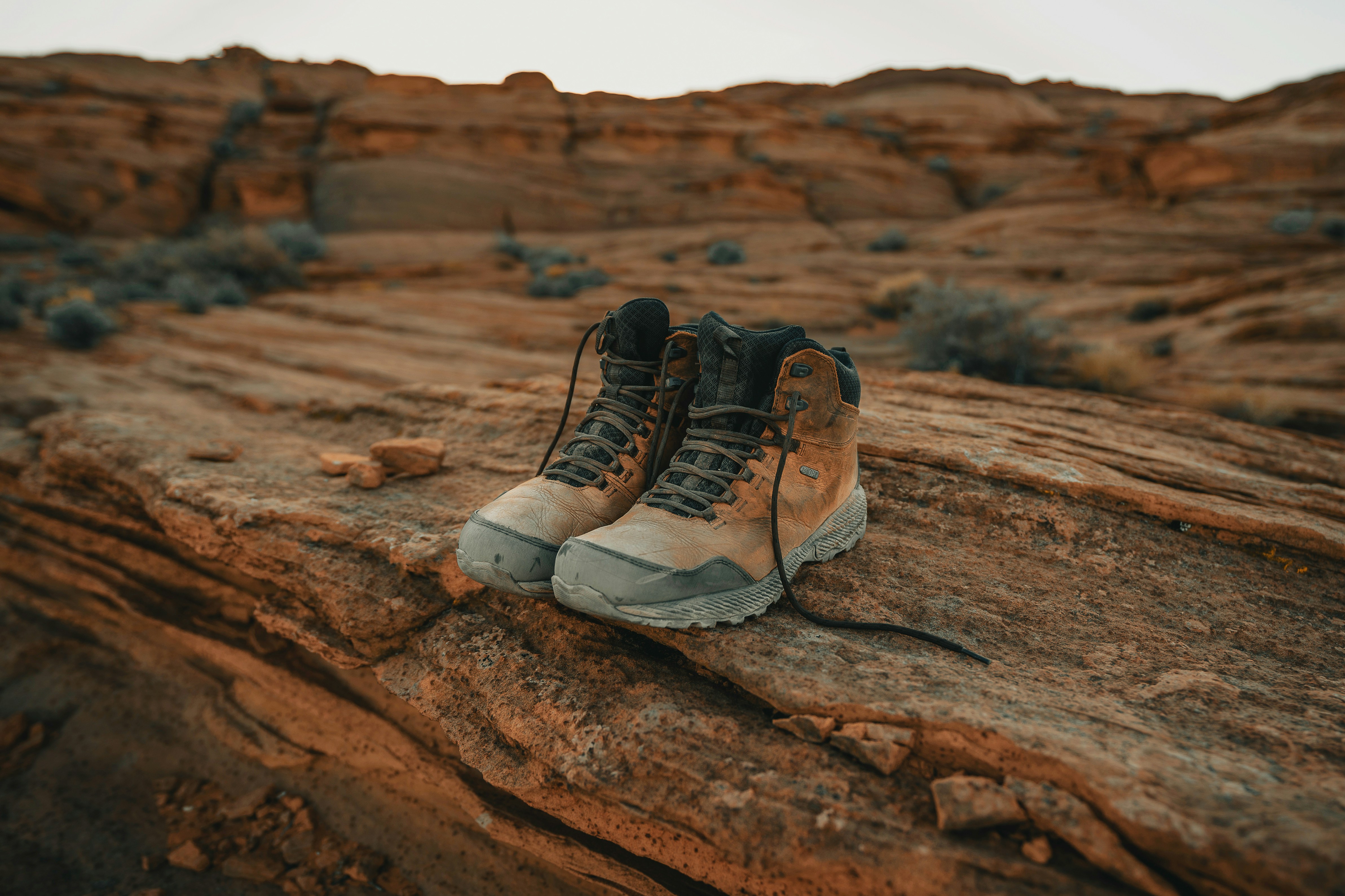 Hiking boots photographed against a dry, rugged desert trail background