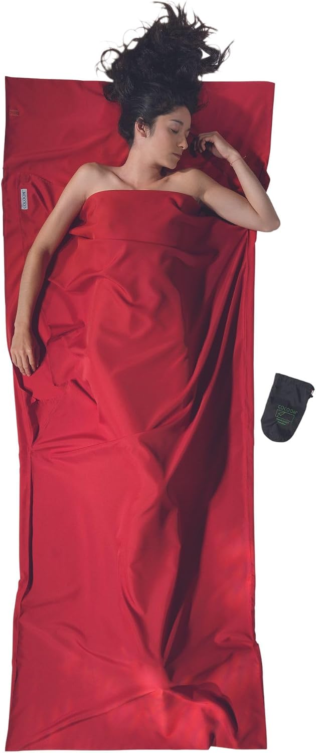 COCOON microfiber TravelSheet sleeping bag liner in red beside its compact sack